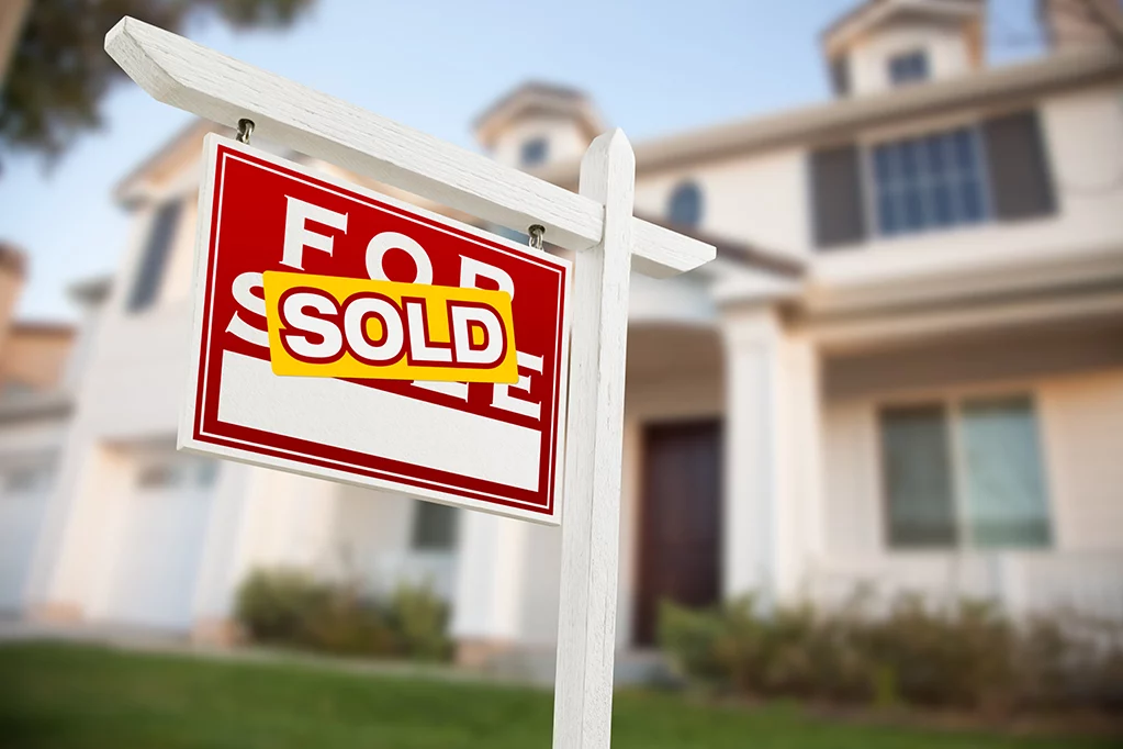 White mansion with sold banner displayed