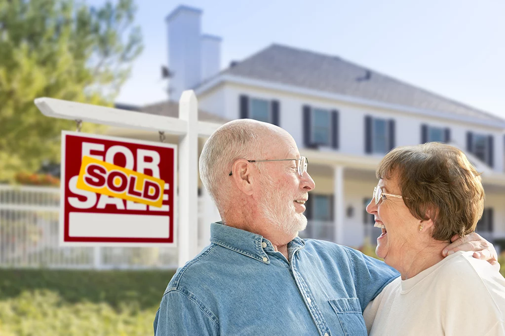 Smiling old couples infront of sold house